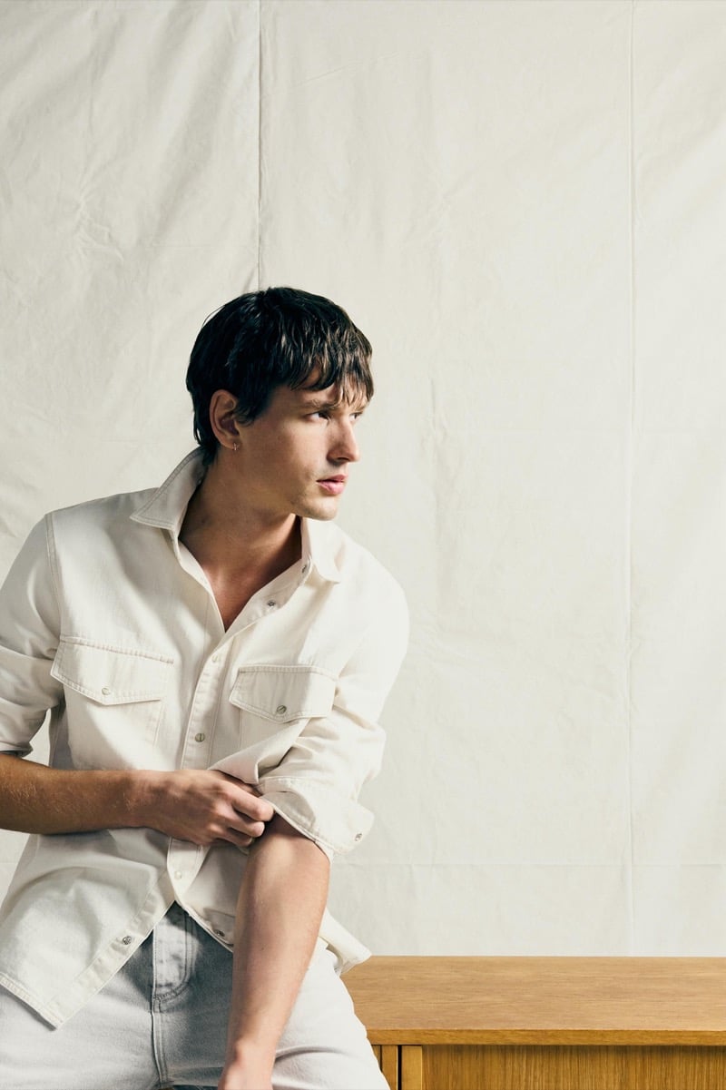 Jegor Venned rolling up the sleeve of a chore shirt with flap chest pockets