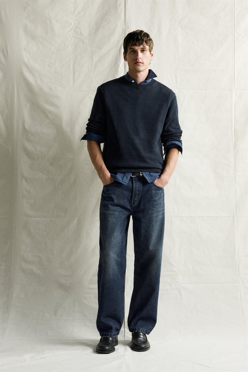 Jegor Venned in a navy crew neck sweater over a chambray shirt with dark denim