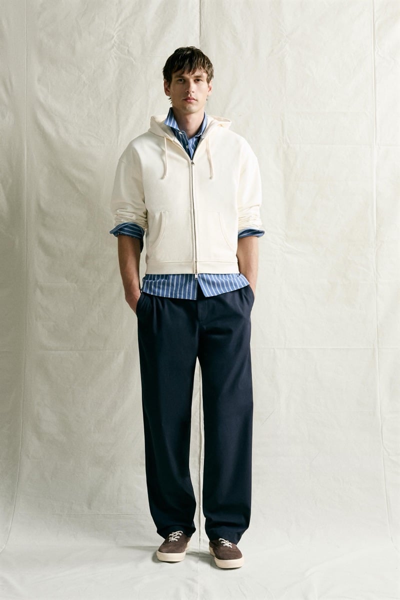 Jegor Venned in an ivory zip hoodie over a striped shirt with roomy navy trousers