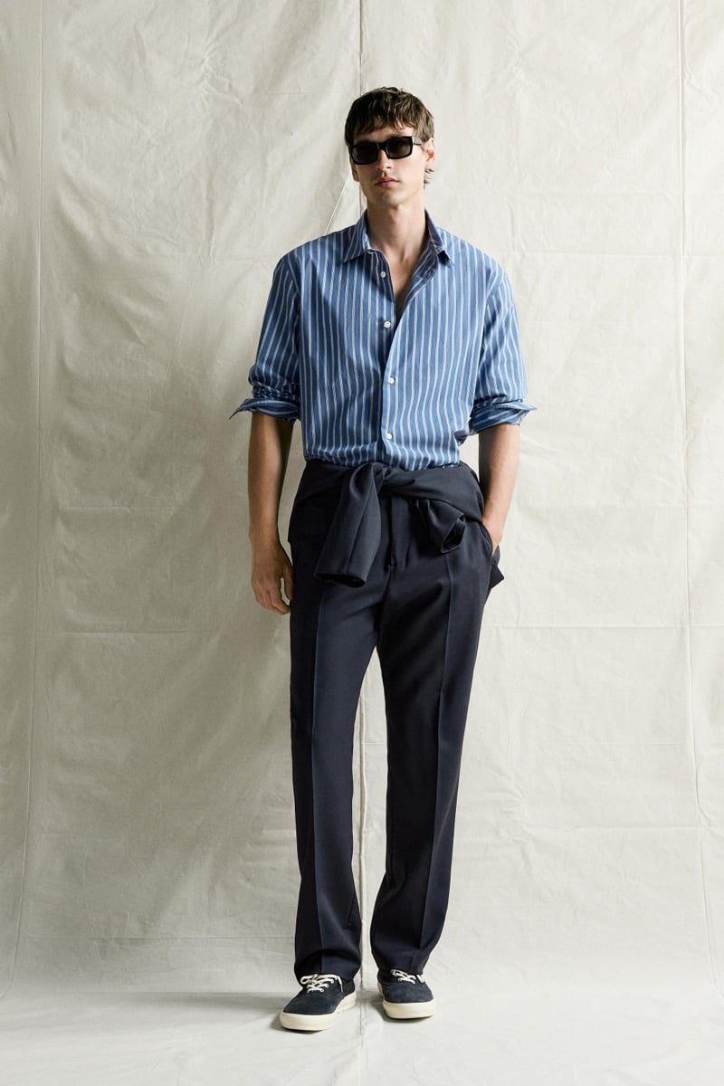 Jegor Venned in a blue striped shirt and sunglasses with a jacket tied at his waist