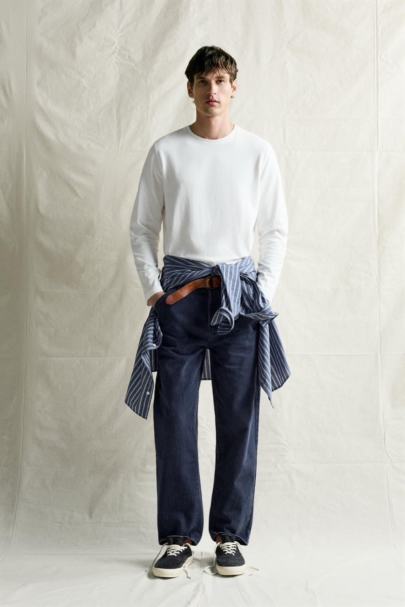 Jegor Venned with a striped shirt tied at his waist over a white long-sleeve tee and dark denim