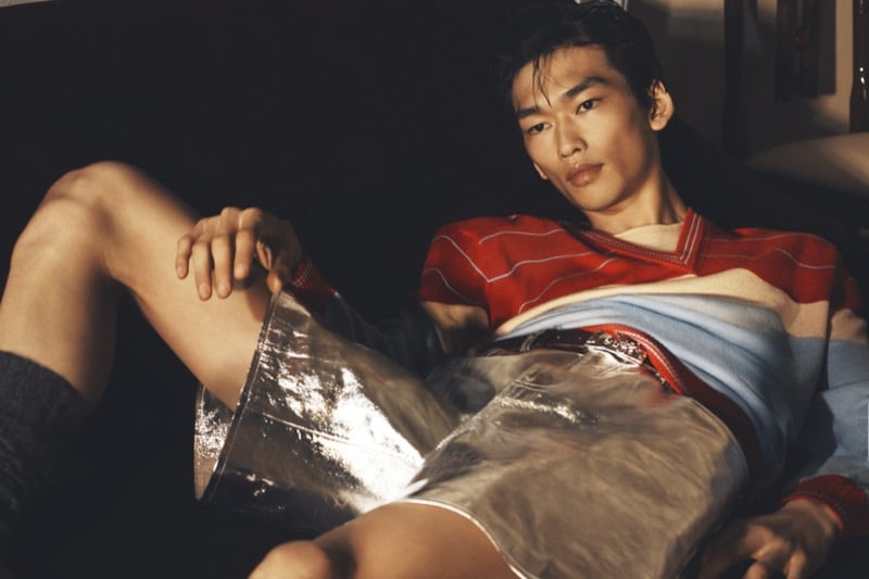 Bai reclining on a sofa in a red striped sweater and shiny silver shorts