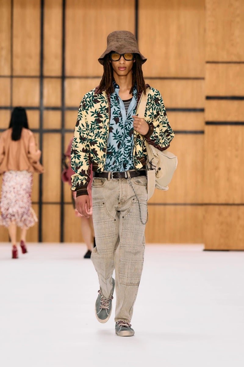 A model in a bucket hat and leaf print bomber jacket over a printed shirt, with washed jeans, for Burberry's summer 2027 collection