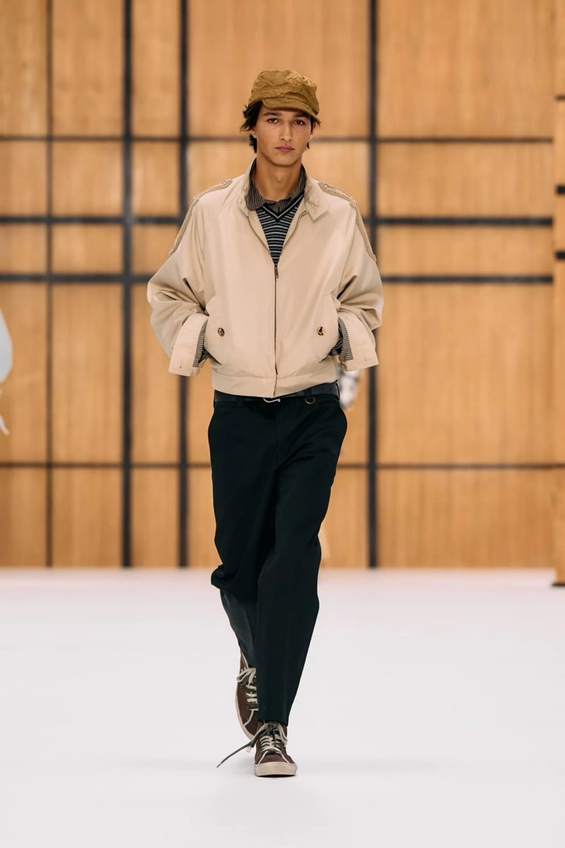 A model in a cap and cropped Harrington jacket over a striped knit, with trousers and sneakers, for Burberry's summer 2027 collection