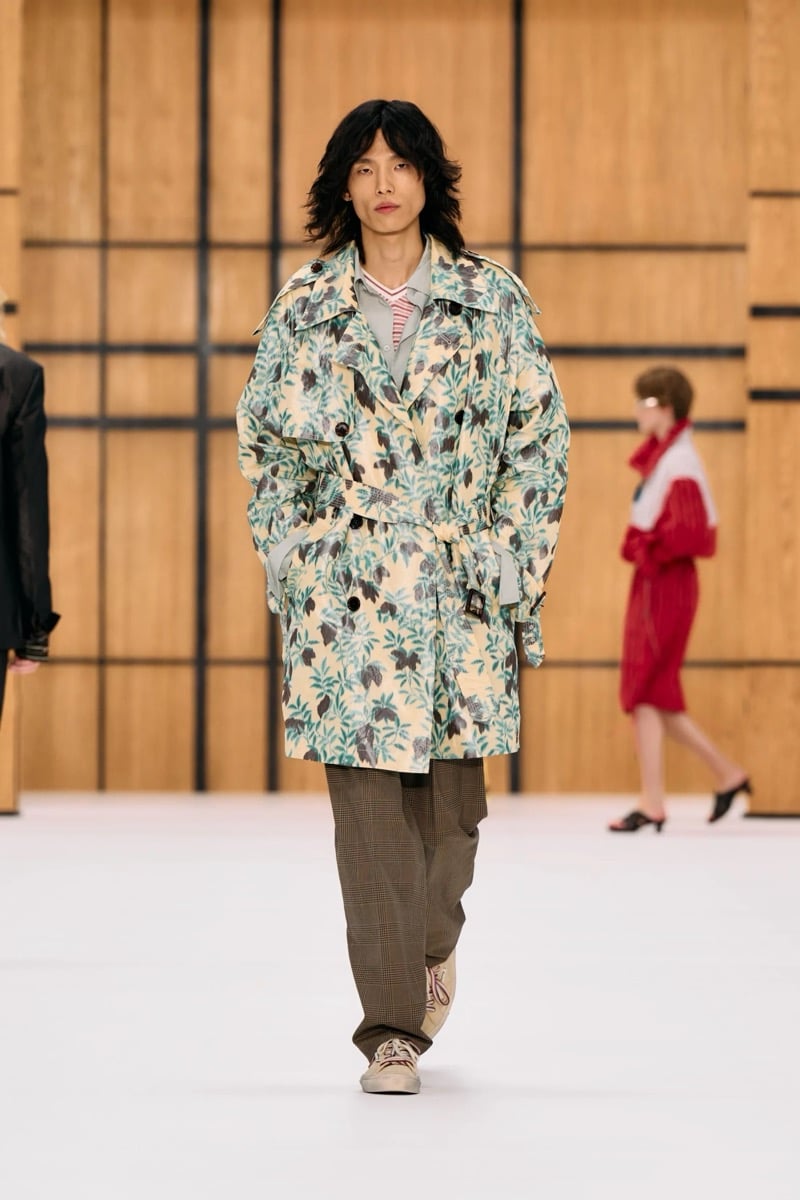 A model in a floral print belted trench coat, with check trousers and sneakers, for Burberry's summer 2027 collection