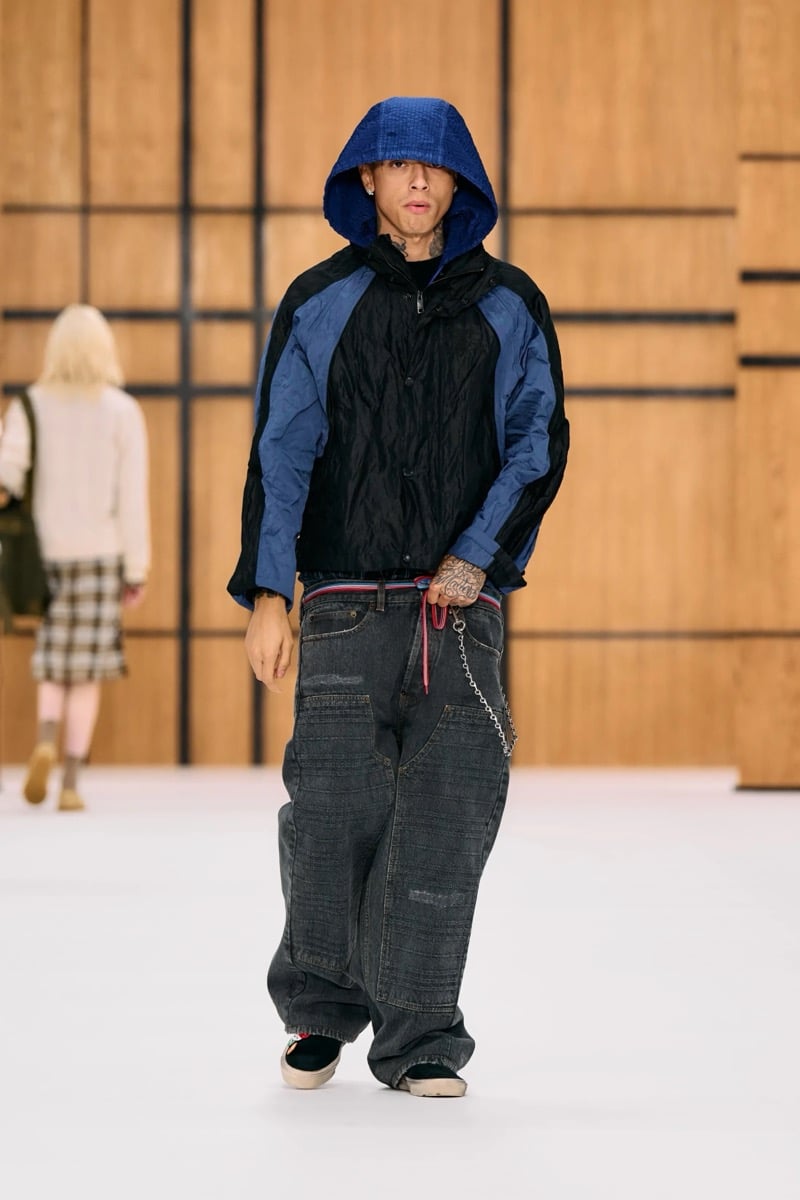 Central Cee wears a hooded paneled jacket with baggy jeans and a wallet chain, for Burberry's summer 2027 collection