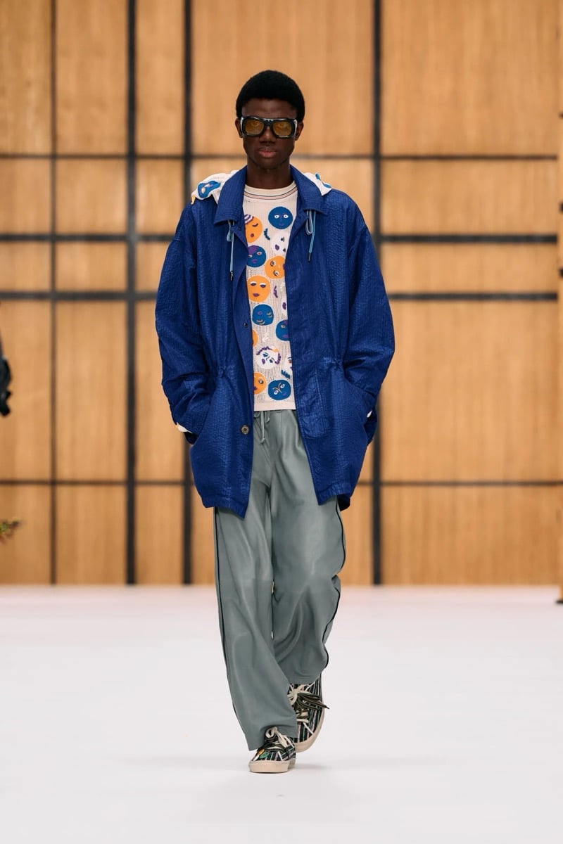 A model in a hooded parka over a face-print knit top, with track pants, for Burberry's summer 2027 collection
