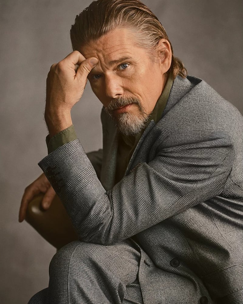 Ethan Hawke rests his head on his hand in a gray checked suit for Canali's fall-winter 2026 campaign.