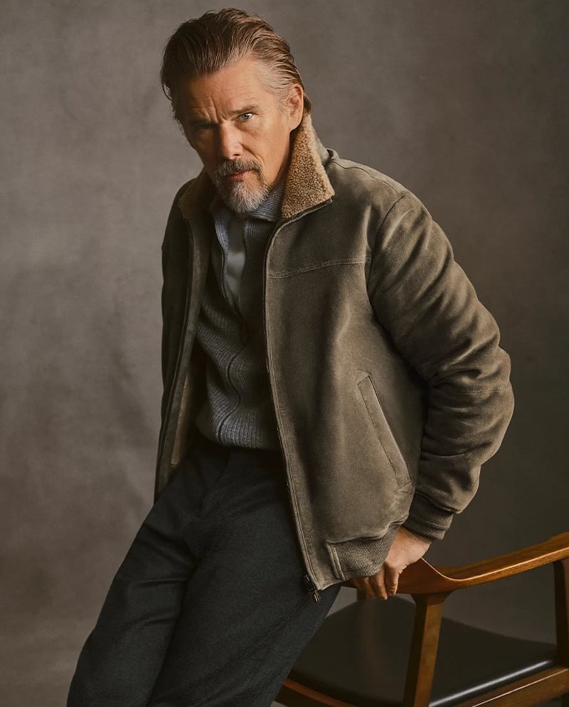 Ethan Hawke leans against a wooden armchair in a suede shearling-collar jacket for Canali's fall-winter 2026 campaign.