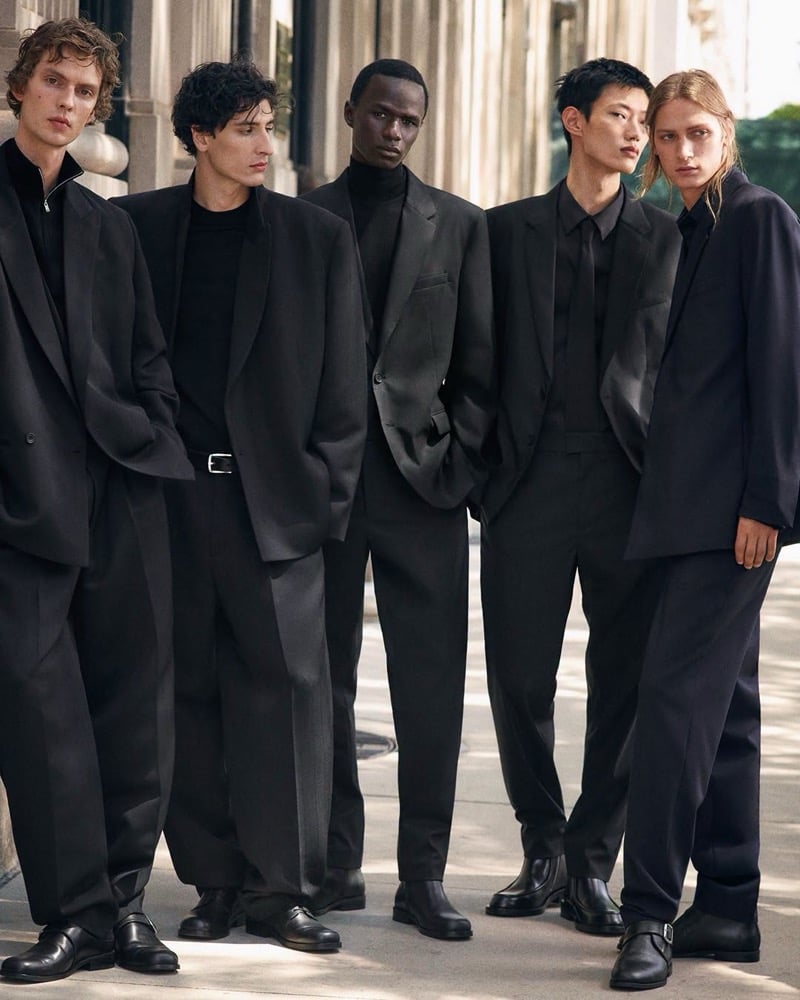 Leon Dame, Lucien Le Neve, Malick Bodian, Hoyong Kim, and Jesse Rinderknecht stand in a row on a sunlit sidewalk in oversized tailoring and leather shoes, for COS's fall 2026 campaign