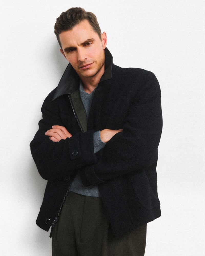 Dave Franco crosses his arms in a J.Crew Barn Jacket over a sweater