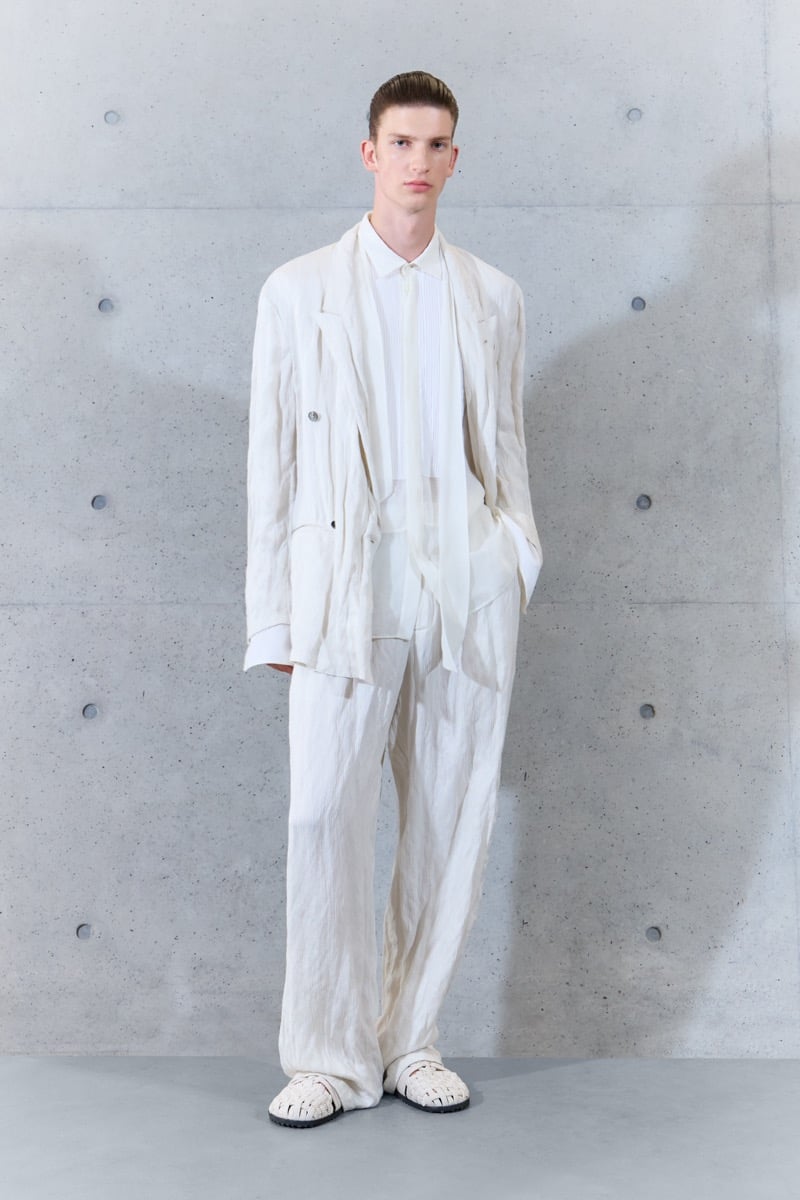 A model in a crinkled double-breasted jacket over a shirt and narrow scarf, with wide-leg trousers, for Emporio Armani's spring-summer 2027 collection