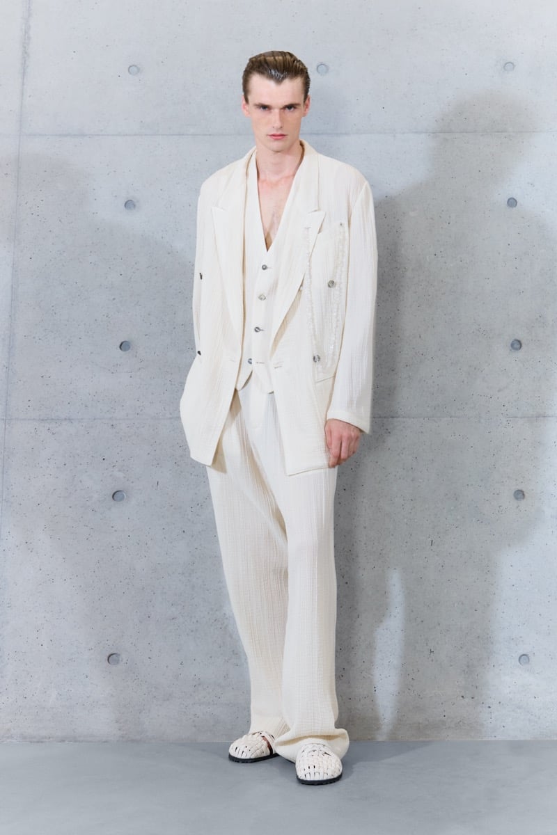 A model in an embellished double-breasted jacket over a bare-chested waistcoat, with wide-leg trousers, for Emporio Armani's spring-summer 2027 collection