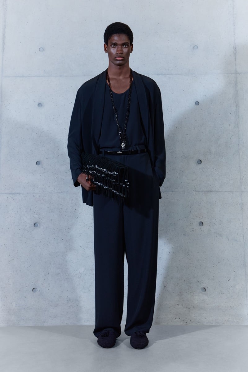 A model in a fluid jacket over a tank, with belted trousers, a fringed clutch, and a pendant necklace, for Emporio Armani's spring-summer 2027 collection