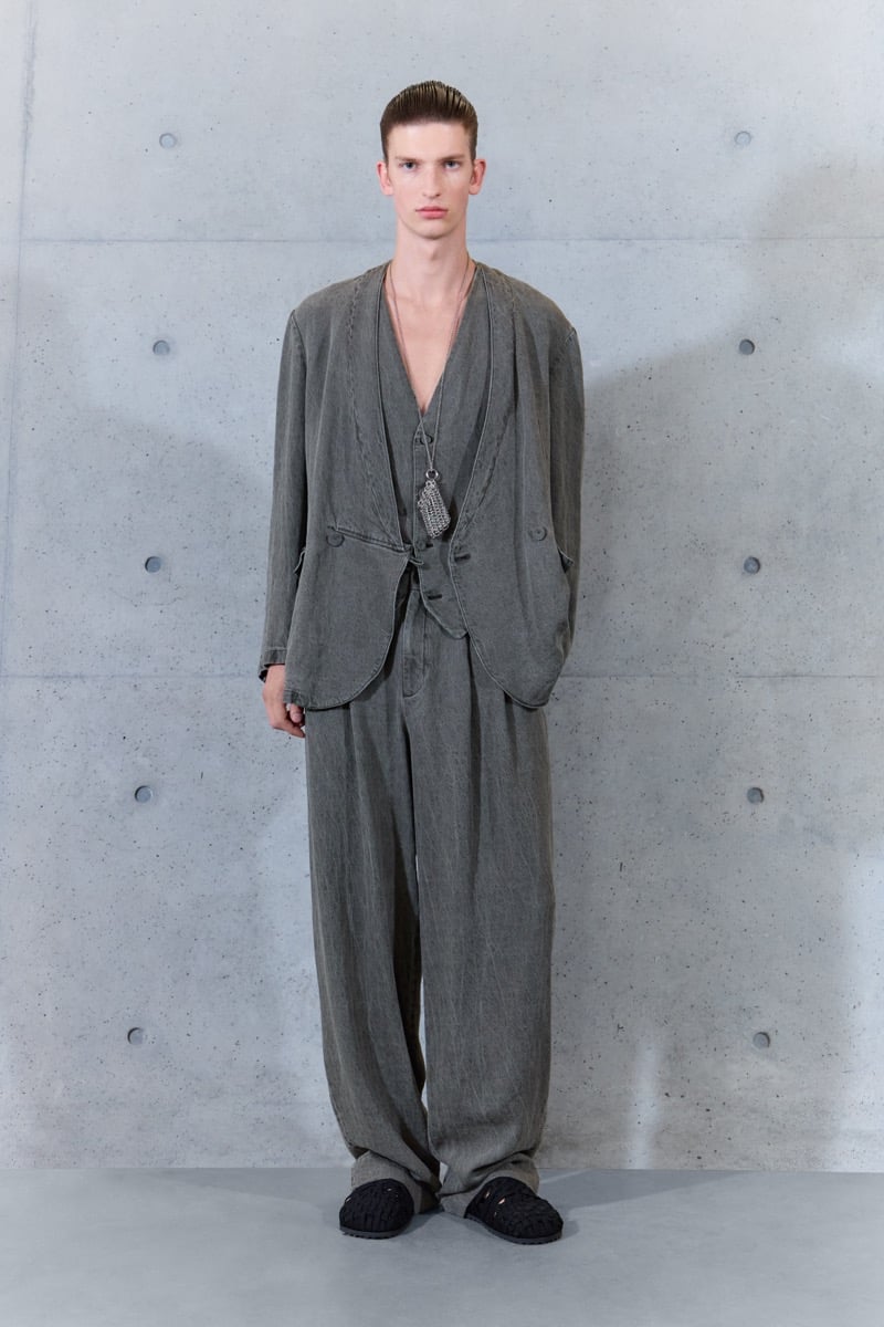 A model in a washed gray jacket and waistcoat with matching trousers and a pendant necklace, for Emporio Armani's spring-summer 2027 collection