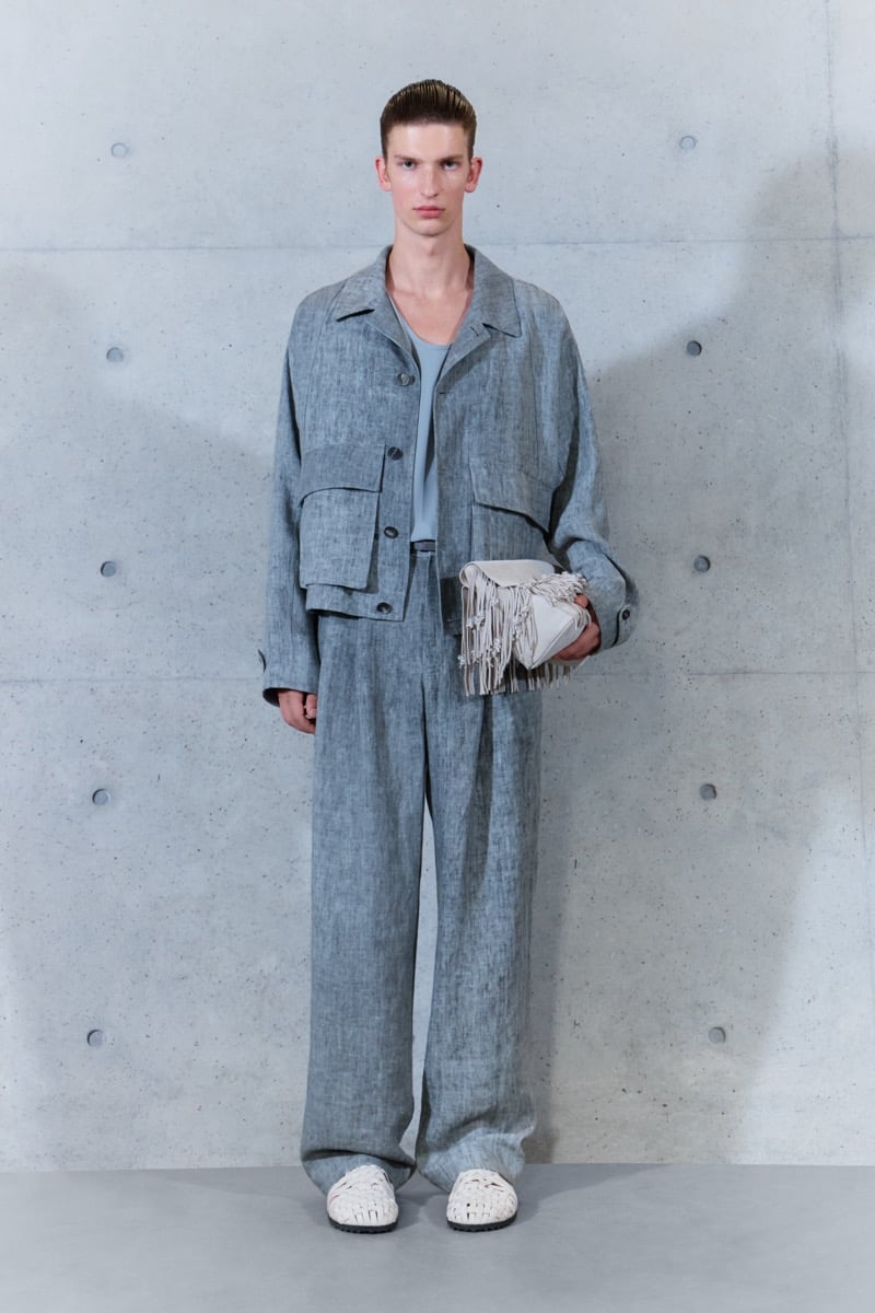 A model in a linen utility jacket and matching trousers over a tank, with a fringed clutch, for Emporio Armani's spring-summer 2027 collection