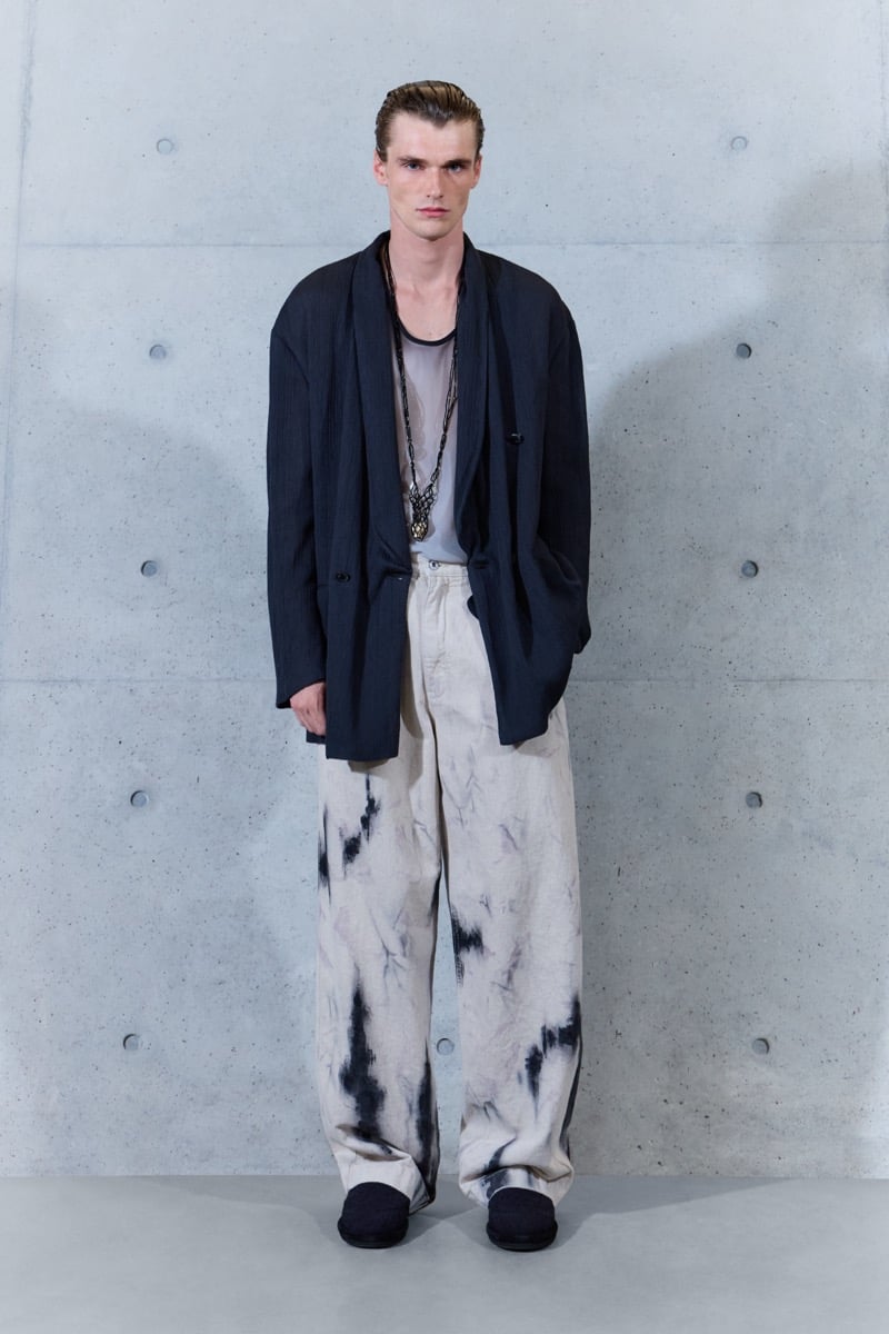 A model in a shawl-collar jacket over a sheer tank, with dyed wide-leg trousers and layered pendant necklaces, for Emporio Armani's spring-summer 2027 collection