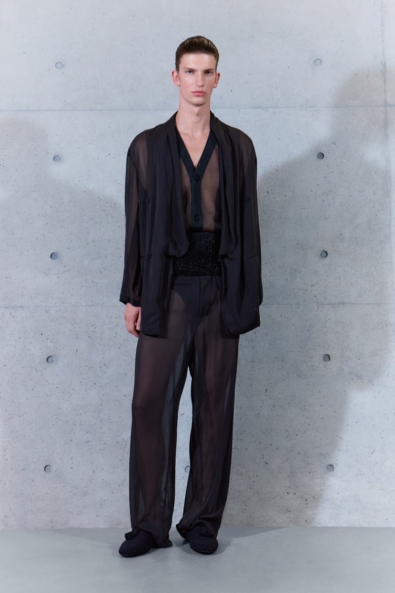 A model in a sheer jacket over a sheer shirt and beaded sash, with sheer trousers, for Emporio Armani's spring-summer 2027 collection