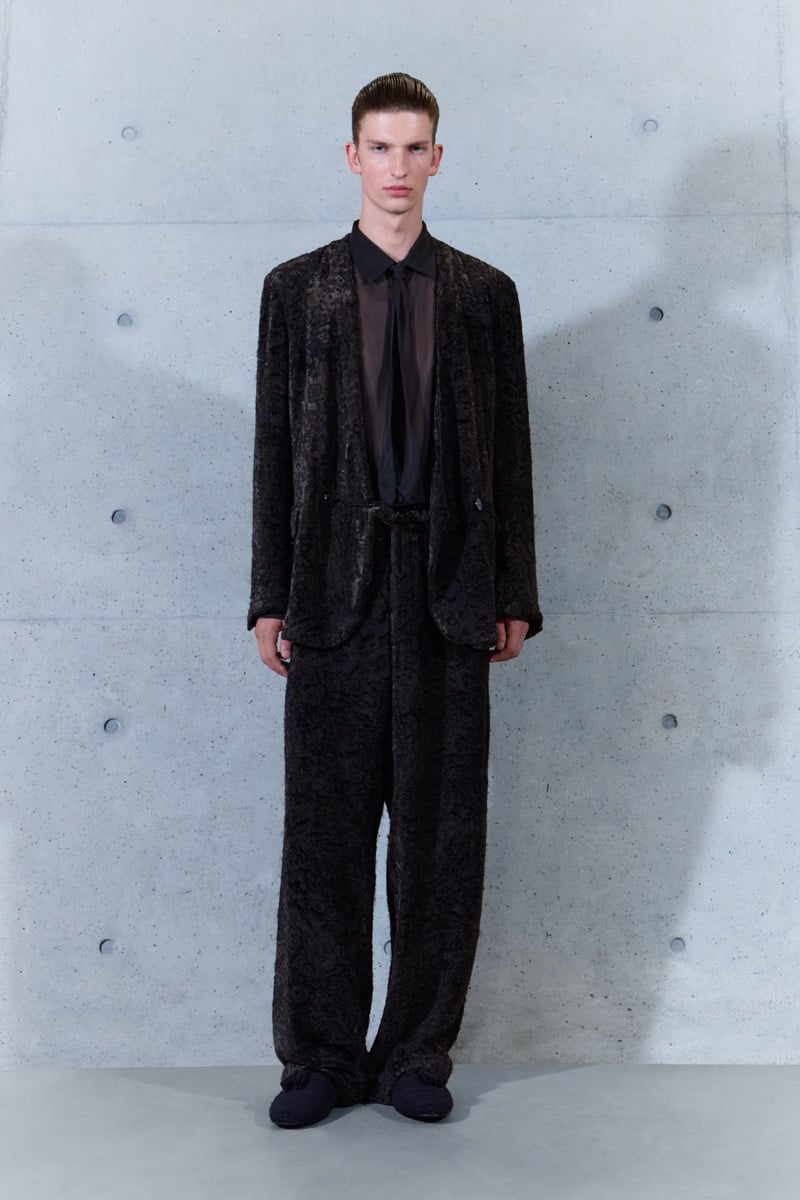 A model in a textured jacket over a sheer shirt and tie, with matching trousers, for Emporio Armani's spring-summer 2027 collection