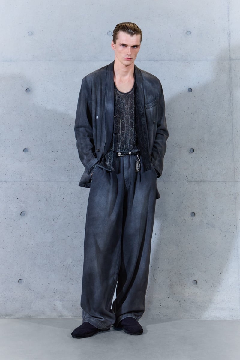 A model in a washed shawl-collar jacket over an openwork knit tank, with pleated wide-leg trousers, for Emporio Armani's spring-summer 2027 collection