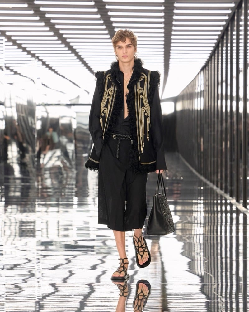 A model in an embroidered vest over a shirt, with long shorts, a woven tote, and strappy sandals, for Fendi's spring-summer 2027 collection