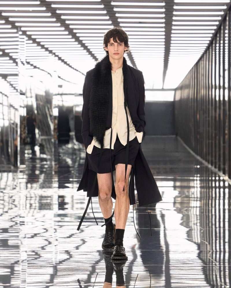 A model in a long coat and fur stole over a band-collar shirt, with shorts, for Fendi's spring-summer 2027 collection