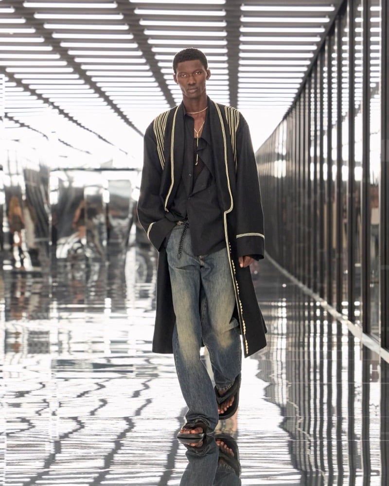 A model in a piped robe coat over a shirt, with washed jeans and sandals, for Fendi's spring-summer 2027 collection