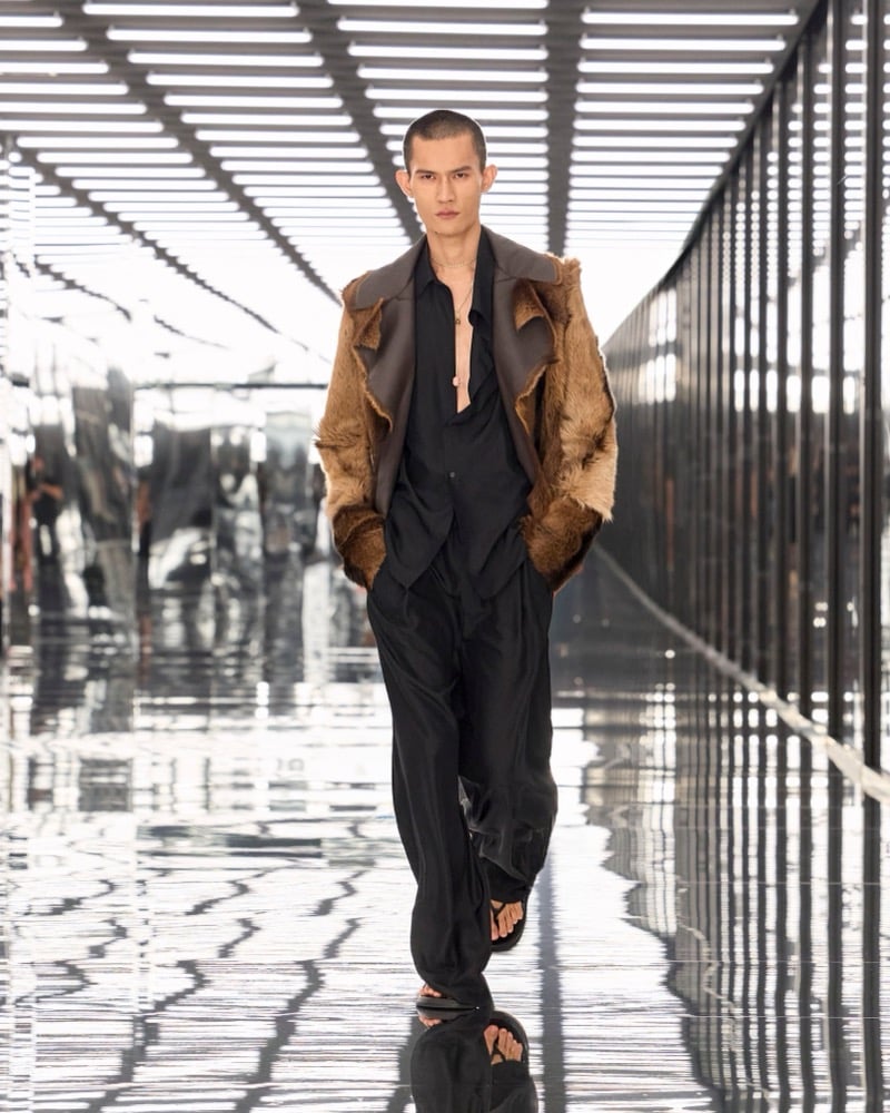 A model in a shaggy jacket with leather lapels over an open shirt, with fluid trousers and sandals, for Fendi's spring-summer 2027 collection