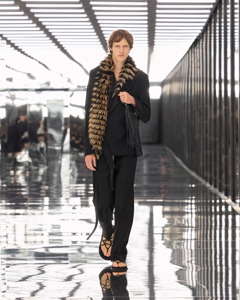 A model in a striped fur stole over a double-breasted jacket and trousers, with a fringed bag and sandals, for Fendi's spring-summer 2027 collection