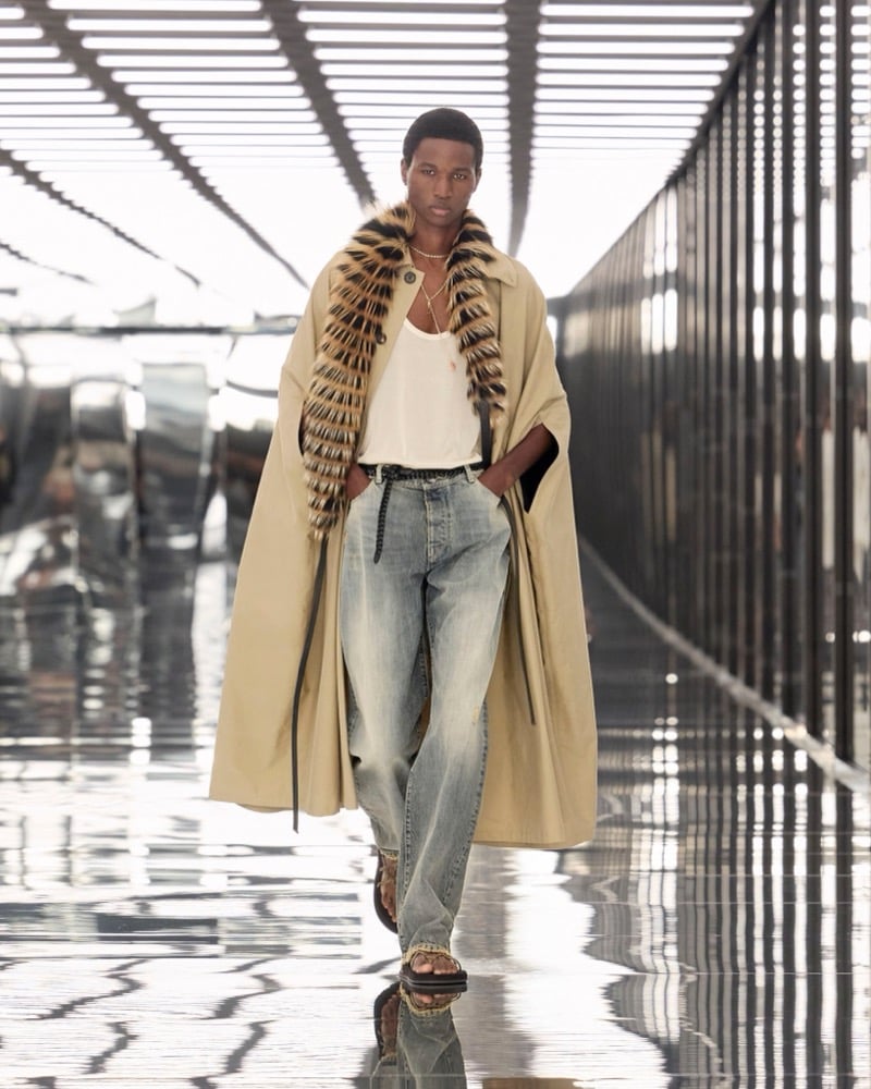 A model in a trench cape and fur stole over a tank, with washed jeans, for Fendi's spring-summer 2027 collection