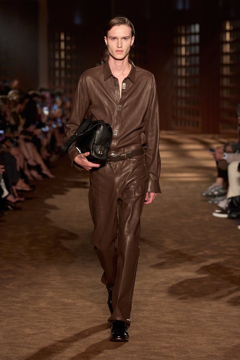 A model in a brown leather shirt and matching leather trousers, carrying a leather bag, for Ferragamo's spring-summer 2027 collection