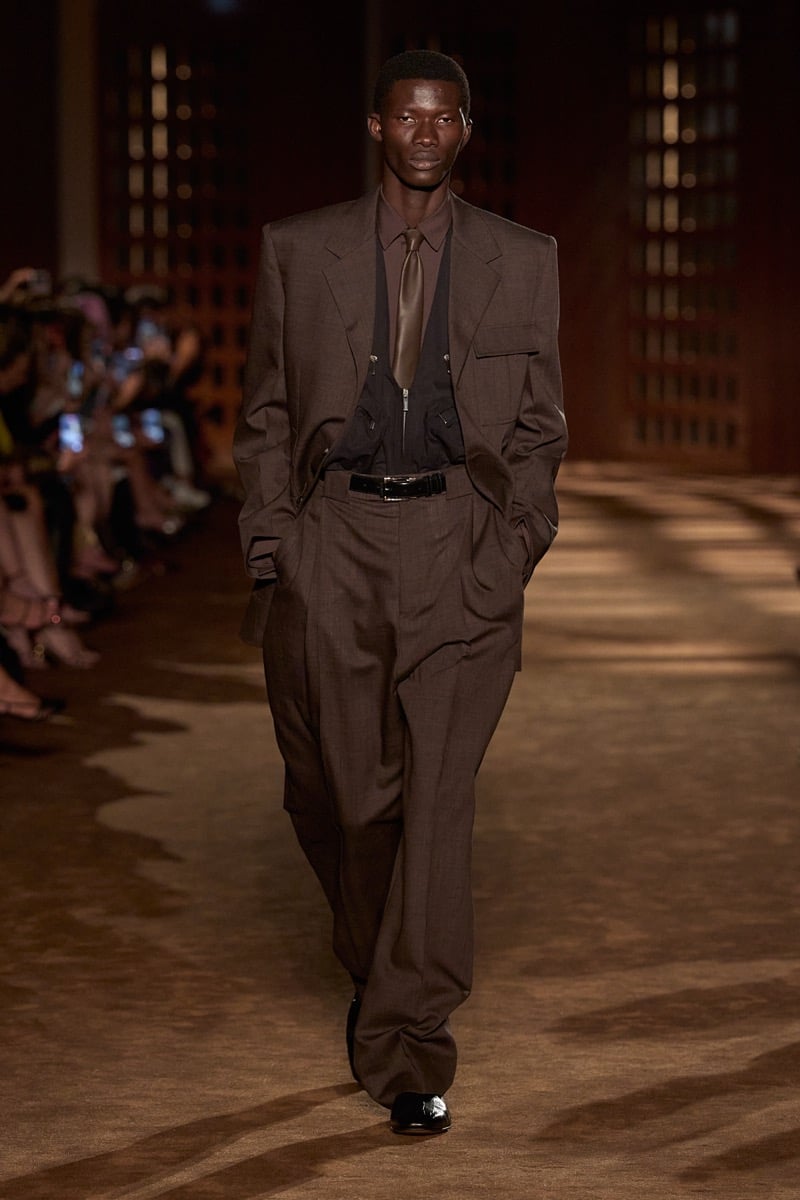 A model in a brown suit over a zip-front vest and tie, with belted high-waisted trousers, for Ferragamo's spring-summer 2027 collection