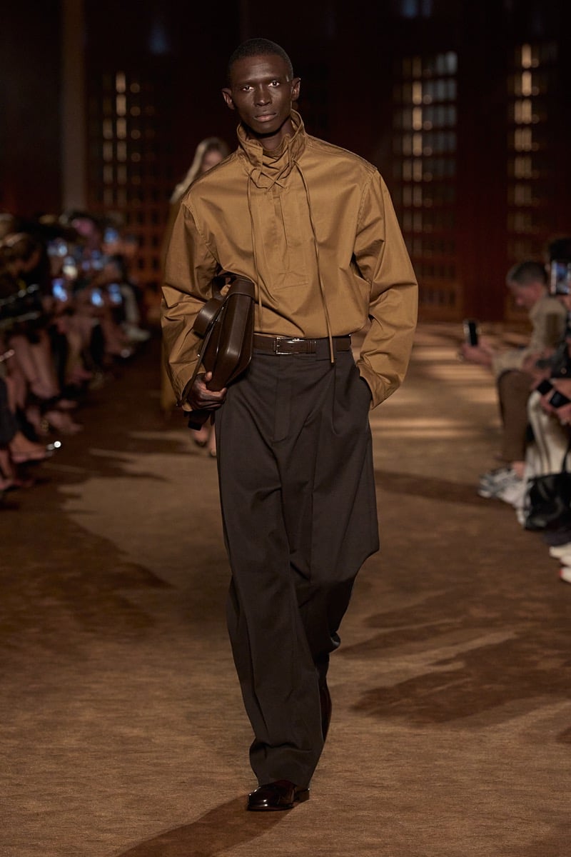 A model in a funnel-neck drawstring shirt and pleated wide trousers, with a leather bag under his arm, for Ferragamo's spring-summer 2027 collection