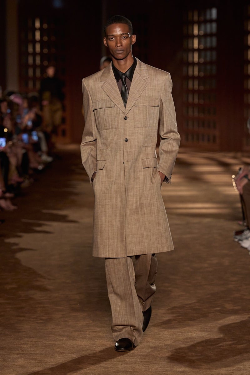 A model in a knee-length patch-pocket coat over a shirt and tie, with matching wide trousers, for Ferragamo's spring-summer 2027 collection