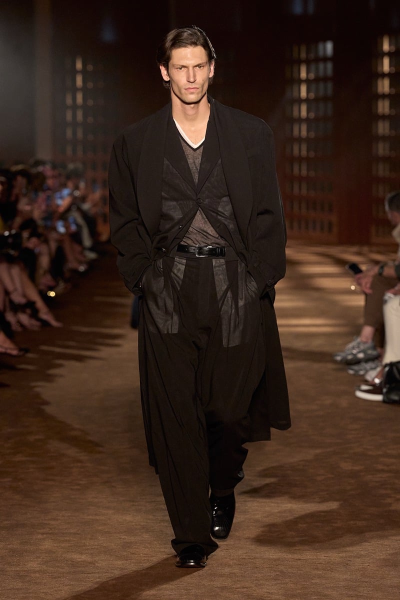 A model in a long coat over translucent layers, with belted wide trousers, for Ferragamo's spring-summer 2027 collection