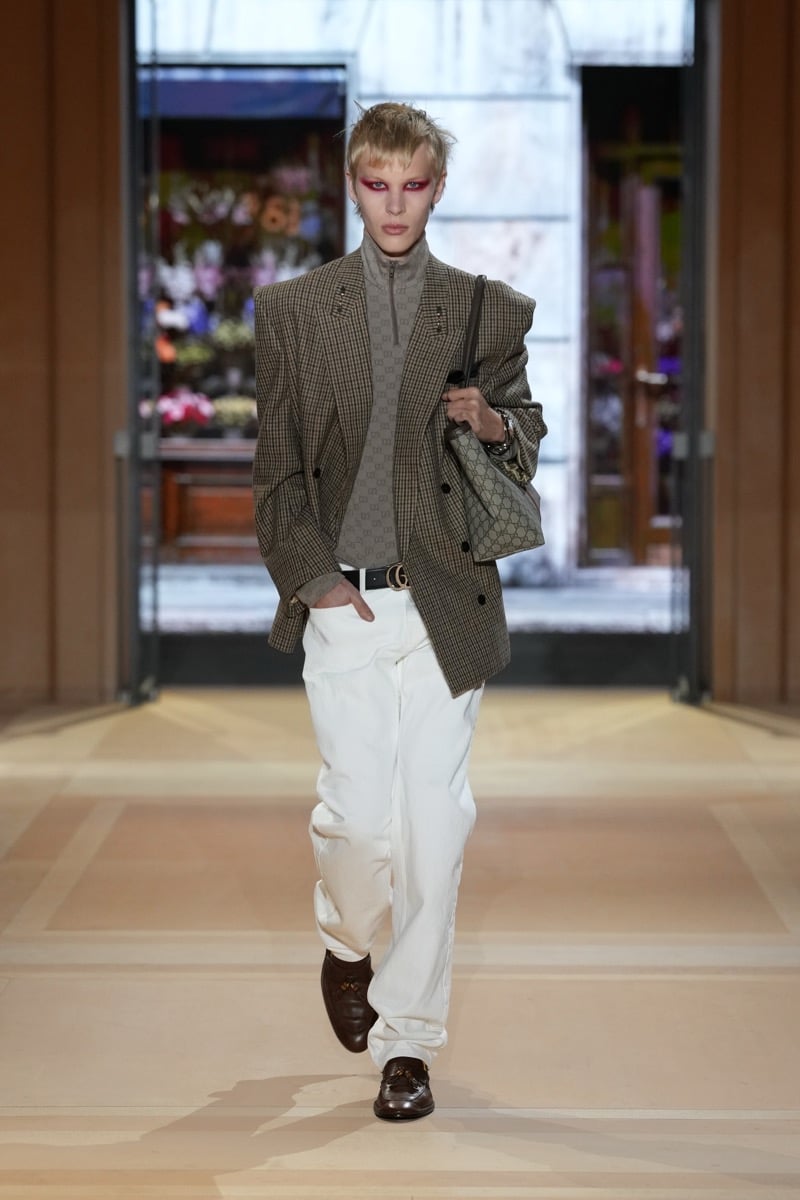 A model in a check blazer over a GG half-zip, with jeans and a GG Supreme tote, for Gucci's spring-summer 2027 collection