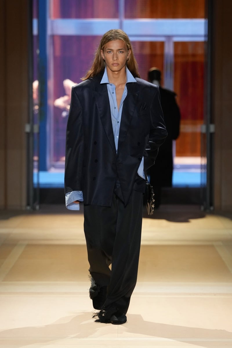 A model in a double-breasted blazer over a striped shirt with turned-back cuffs, with wide trousers, for Gucci's spring-summer 2027 collection