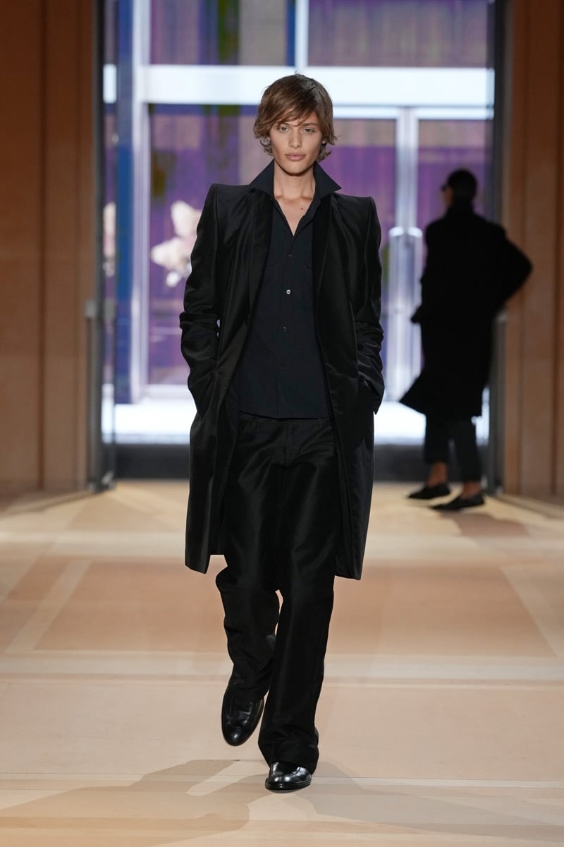 A model in a long coat over a buttoned shirt, with wide trousers and loafers, for Gucci's spring-summer 2027 collection