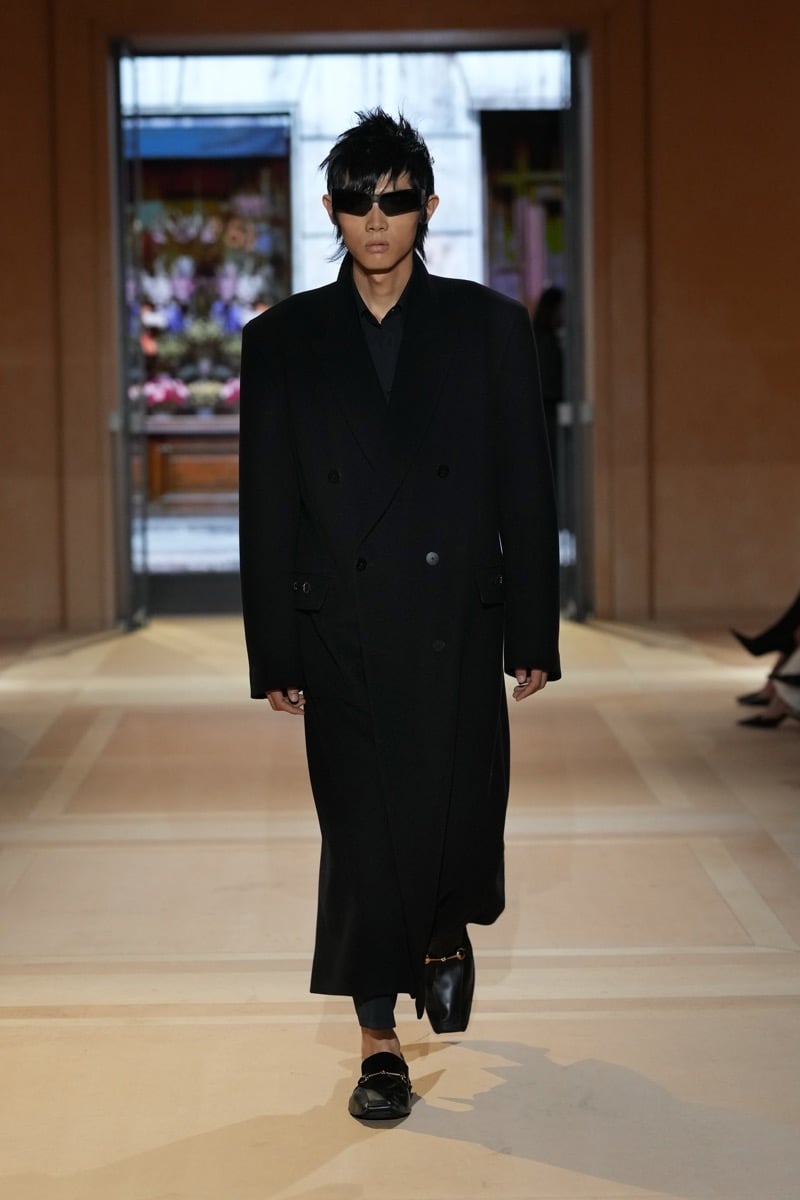 A model with spiked hair and sunglasses in a long double-breasted coat and Horsebit loafers, for Gucci's spring-summer 2027 collection