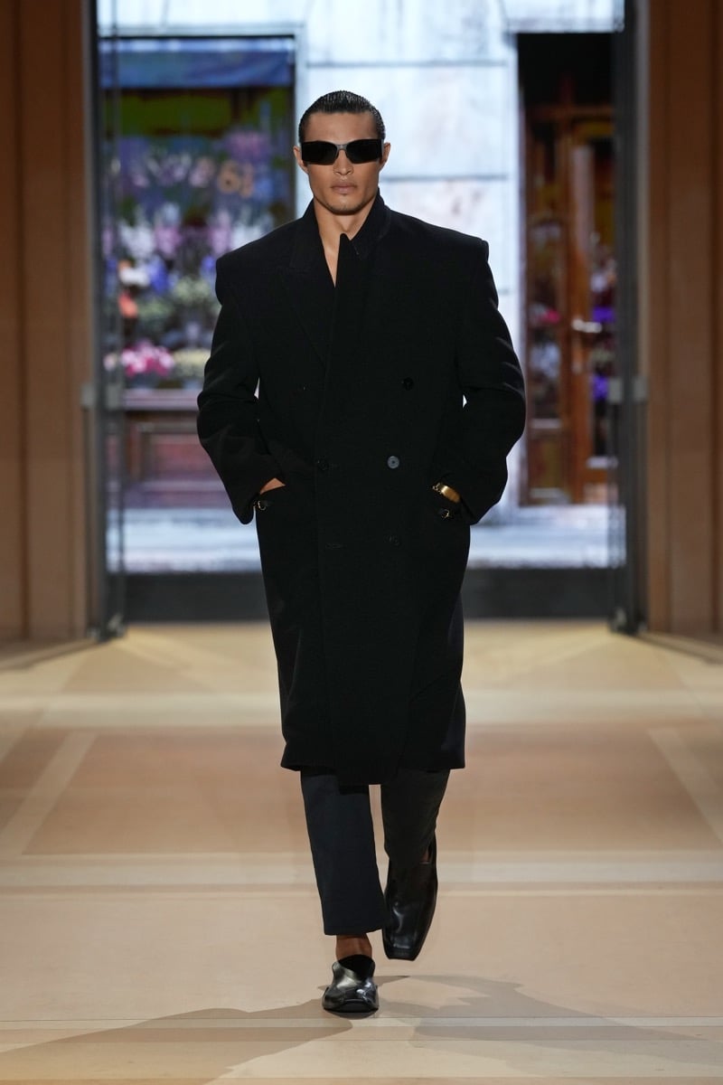 A model in sunglasses and an oversized double-breasted overcoat, with trousers and Horsebit loafers, for Gucci's spring-summer 2027 collection