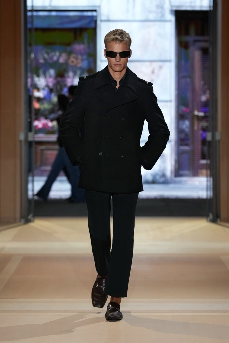 A model in sunglasses and a double-breasted peacoat, with cropped trousers and Horsebit loafers, for Gucci's spring-summer 2027 collection