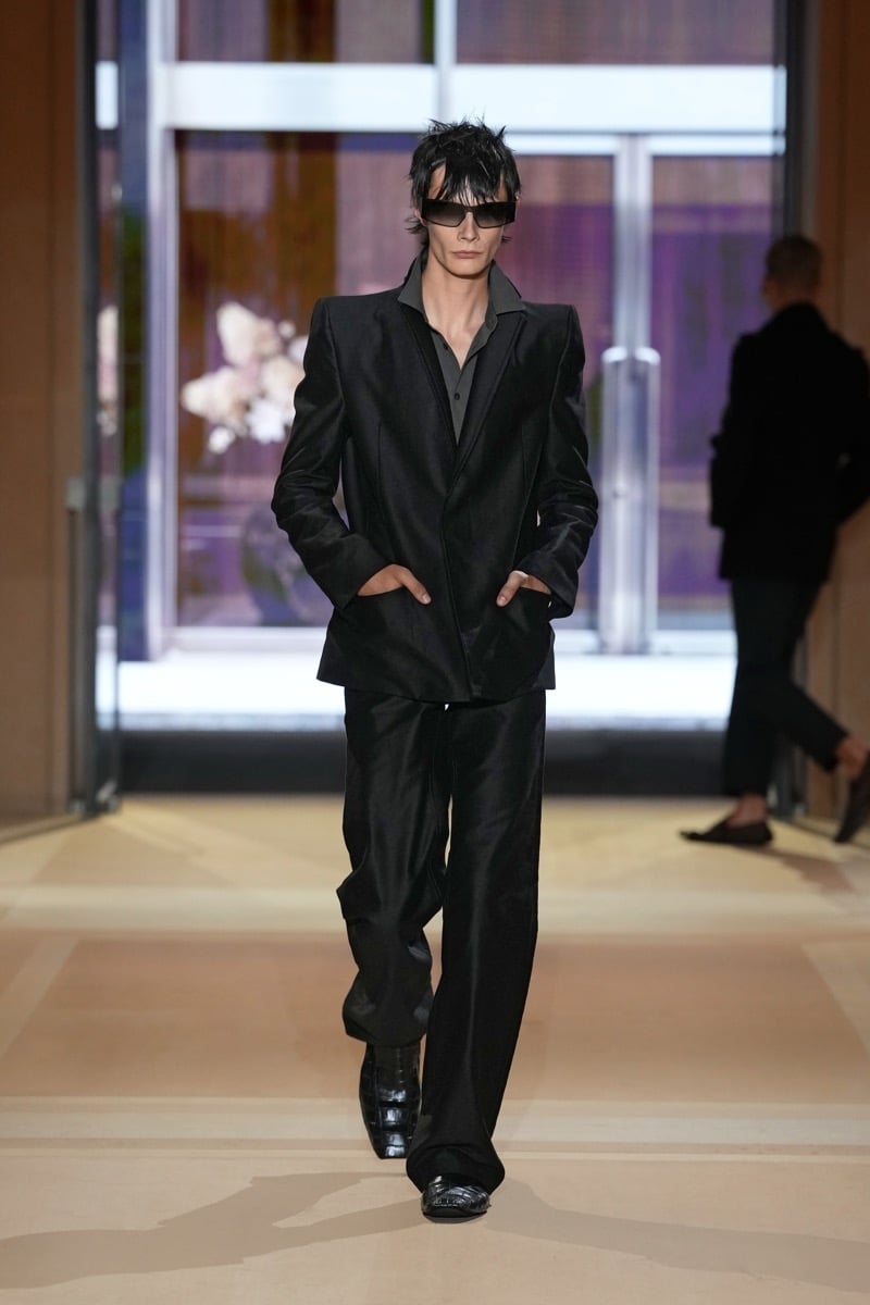 A model with spiked hair in a sharp-shouldered suit over a shirt, with wide trousers, for Gucci's spring-summer 2027 collection
