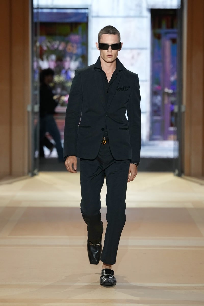 A model in sunglasses and a slim suit over an open-collar shirt, with Horsebit loafers, for Gucci's spring-summer 2027 collection