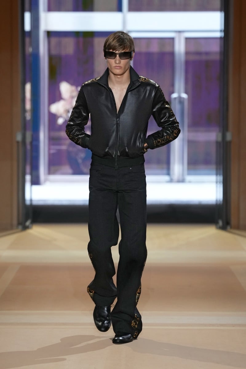A model in a track jacket and flared trousers trimmed with gold logo tape, for Gucci's spring-summer 2027 collection