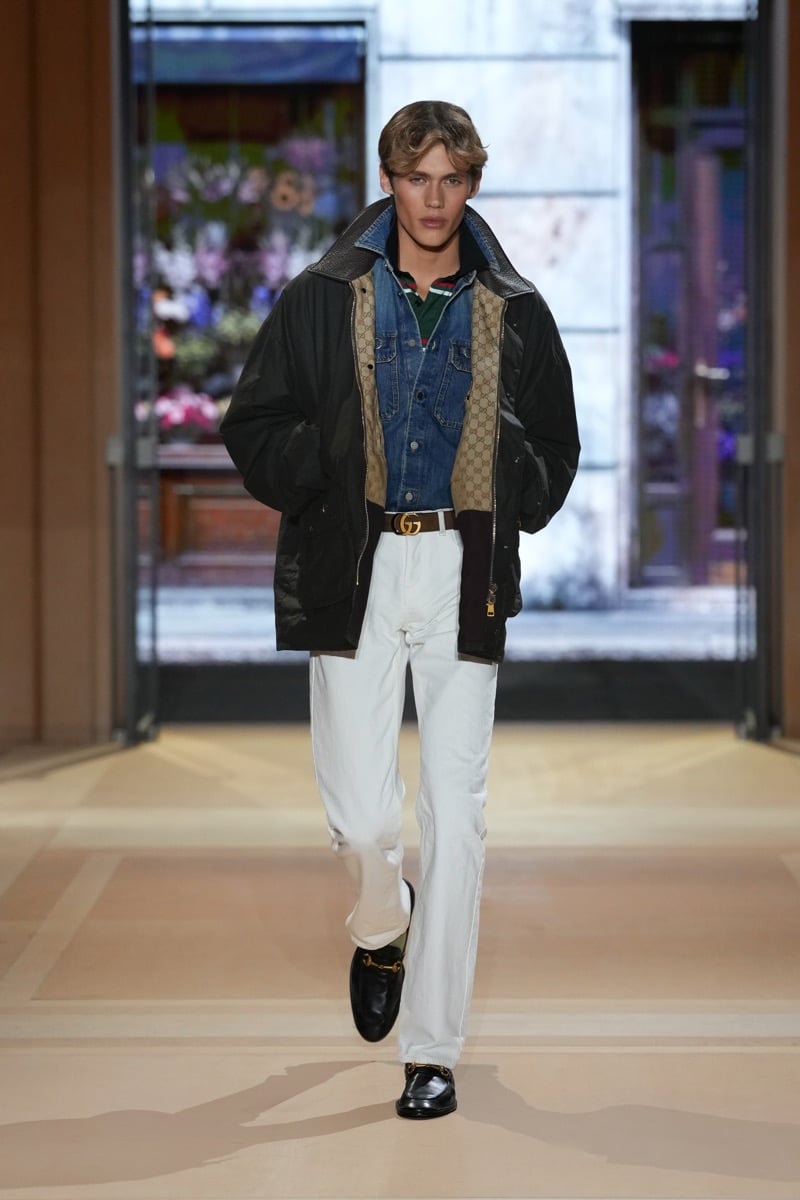 A model in a waxed jacket with GG canvas lining over a denim jacket and rugby shirt, with jeans, for Gucci's spring-summer 2027 collection
