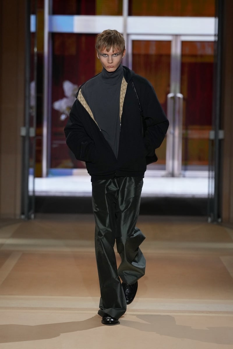A model in a zip jacket with GG canvas lining over a turtleneck, with wide trousers, for Gucci's spring-summer 2027 collection