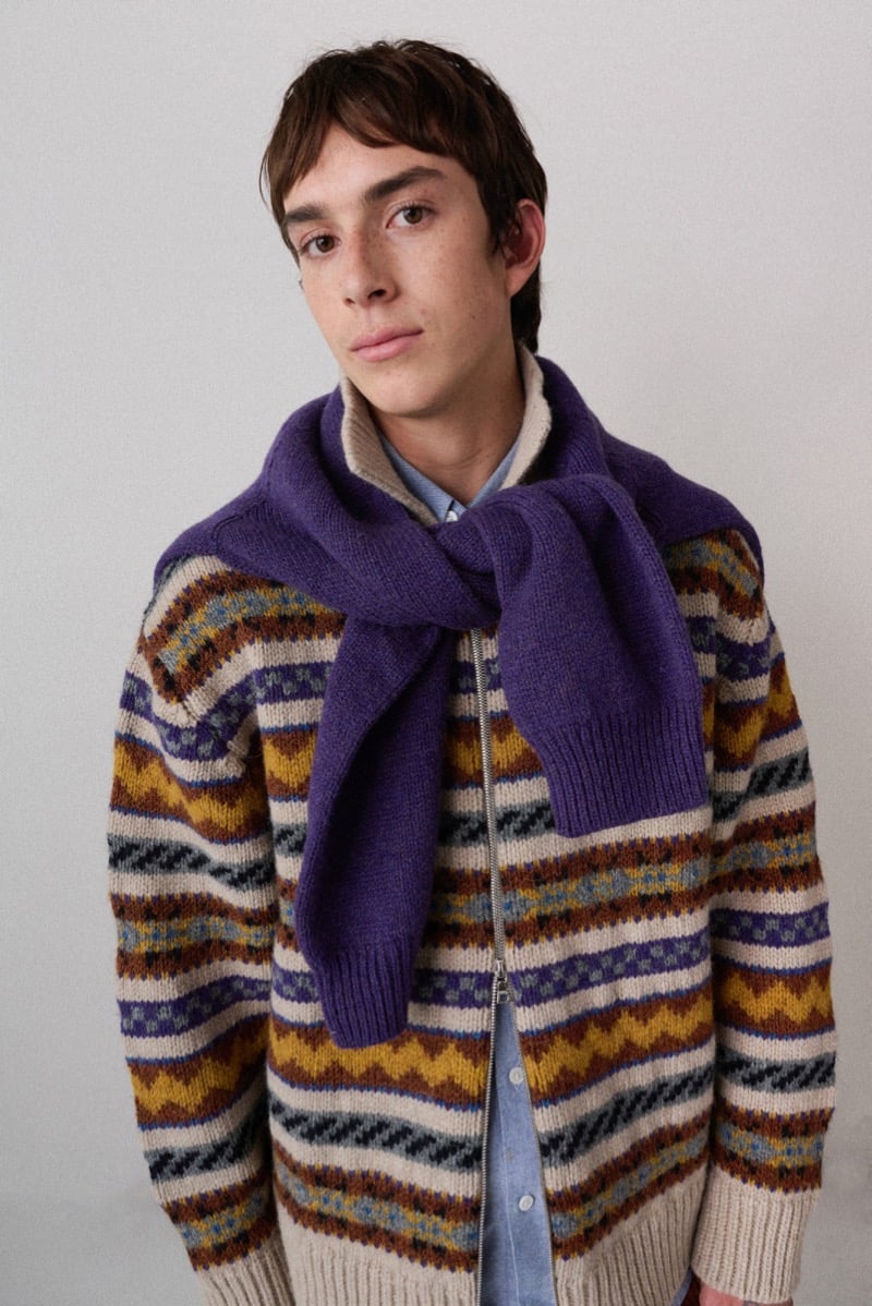 A model in a multicolor Fair Isle cardigan with a purple scarf tied around the neck, for Howlin's fall-winter 2026 collection
