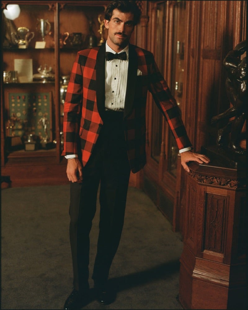 A model wears a red and black buffalo-check shawl-collar dinner jacket with a pleated formal shirt, a bow tie, and dark evening trousers, for J. Press fall-winter 2026