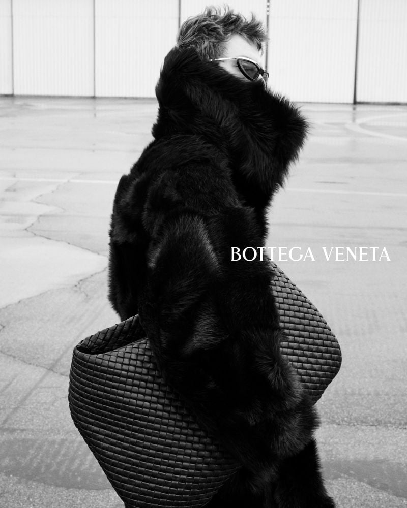 Leon Dame in profile with sunglasses and a raised shearling collar, holding an oversized Intrecciato leather bag