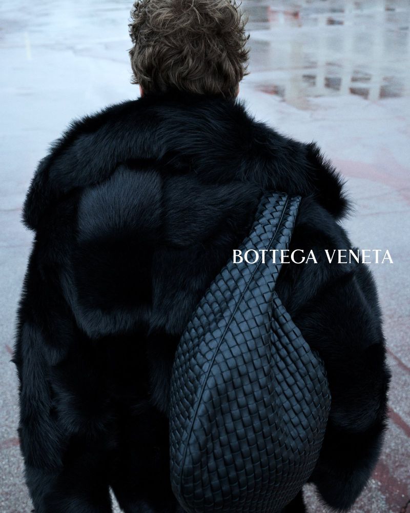 Leon Dame seen from behind in a shearling coat with a large Intrecciato leather bag slung over his shoulder